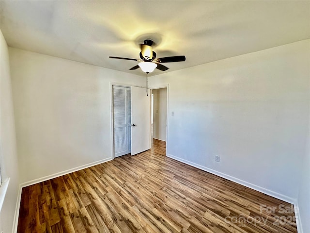 unfurnished bedroom with a ceiling fan, a closet, baseboards, and wood finished floors