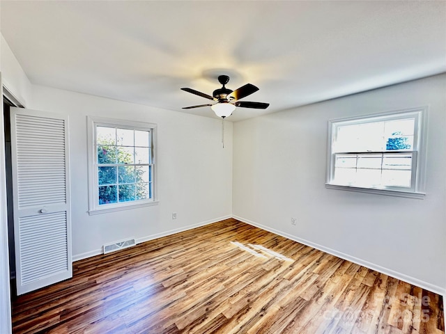 spare room featuring baseboards, visible vents, ceiling fan, and wood finished floors