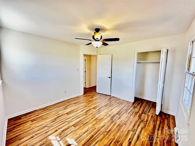 unfurnished bedroom featuring a closet, wood finished floors, a ceiling fan, and baseboards