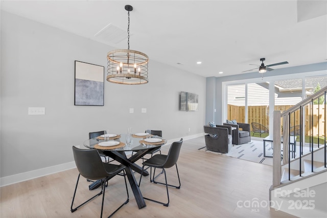 dining room with light wood-style floors, stairway, and baseboards