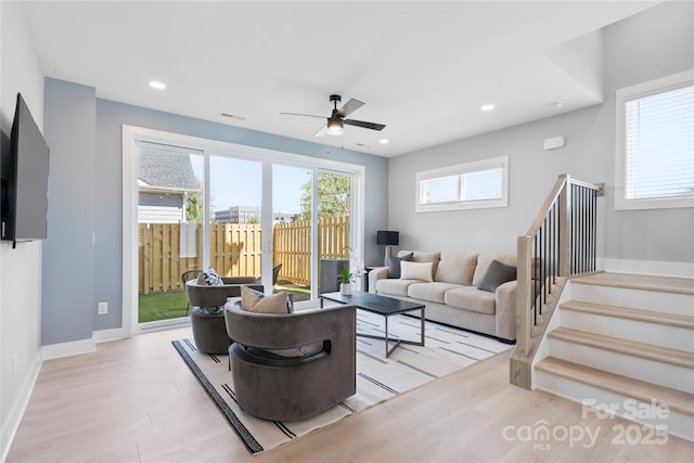 living area with light wood-style floors, a wealth of natural light, stairway, and recessed lighting