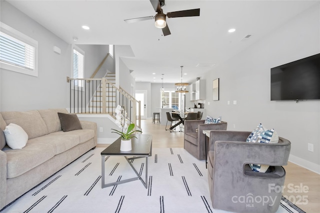 living room with stairs, recessed lighting, a wealth of natural light, and light wood-style floors