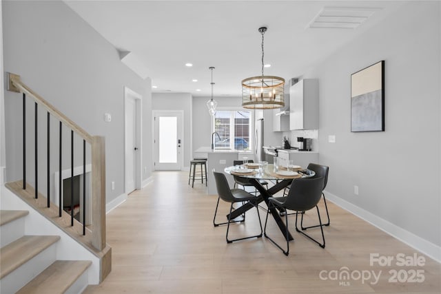 dining area featuring light wood finished floors, baseboards, stairway, and recessed lighting