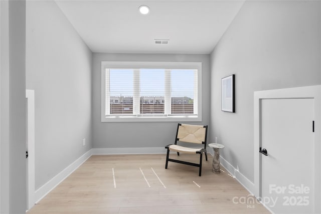 sitting room with light wood finished floors, visible vents, and baseboards