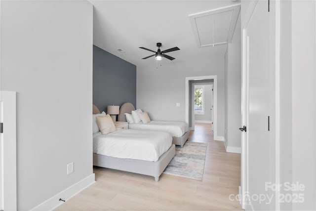 bedroom featuring visible vents, attic access, light wood-style floors, ceiling fan, and baseboards