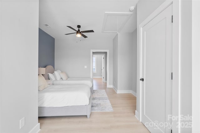 bedroom featuring attic access, visible vents, baseboards, ceiling fan, and light wood-type flooring