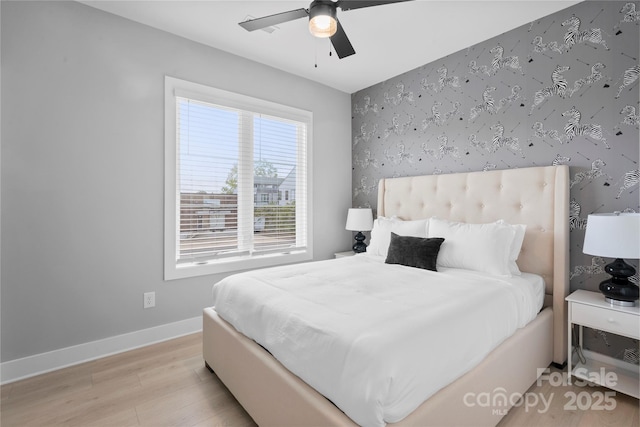 bedroom with wallpapered walls, baseboards, a ceiling fan, light wood-style flooring, and an accent wall