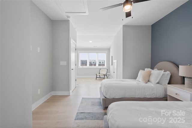 bedroom with baseboards, ceiling fan, attic access, and light wood-style floors