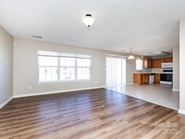 unfurnished living room featuring visible vents, baseboards, and wood finished floors