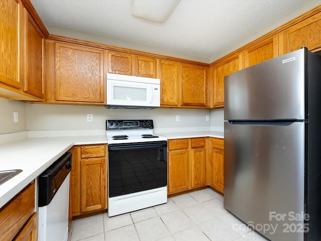 kitchen featuring a textured ceiling, light countertops, white appliances, and brown cabinetry