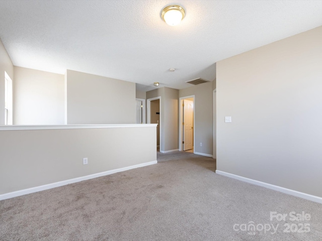 unfurnished room featuring baseboards, a textured ceiling, visible vents, and carpet flooring