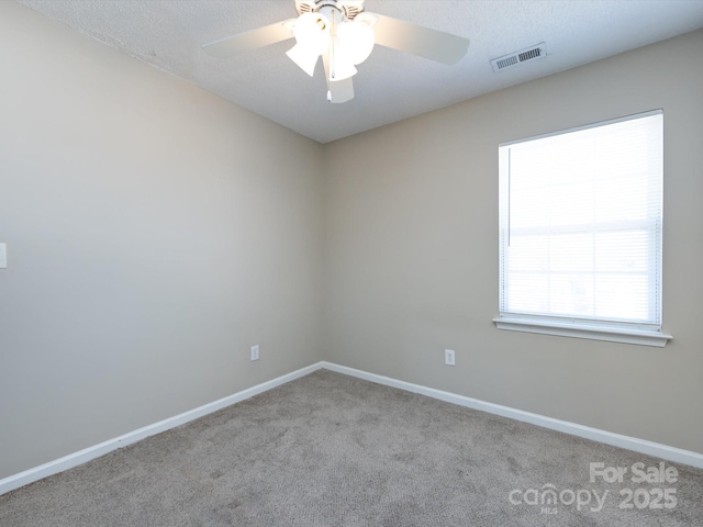 unfurnished room with carpet floors, visible vents, ceiling fan, a textured ceiling, and baseboards