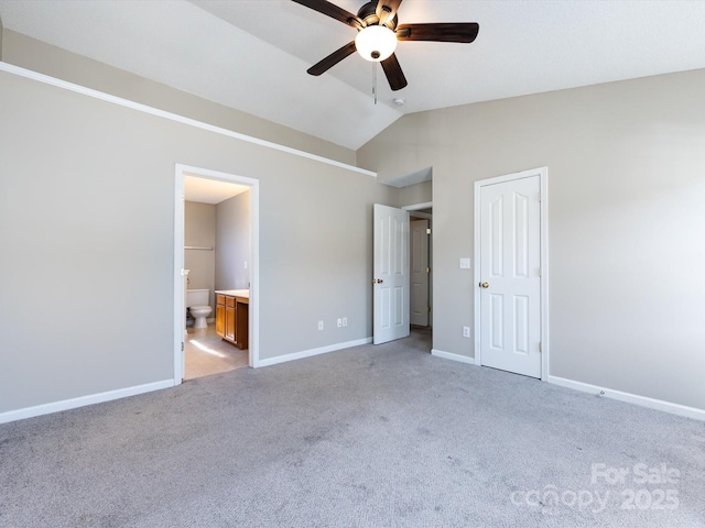unfurnished bedroom featuring light carpet, vaulted ceiling, connected bathroom, and baseboards