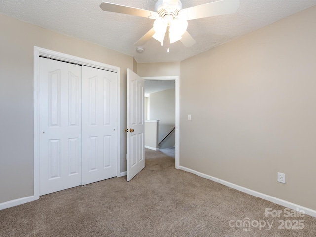 unfurnished bedroom featuring carpet, a closet, a textured ceiling, and baseboards