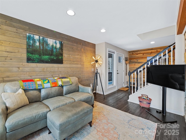 living room featuring wooden walls, stairs, wood finished floors, and recessed lighting