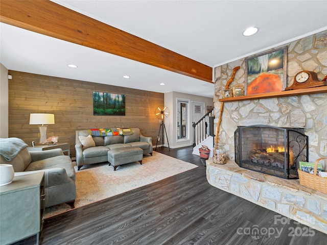 living area featuring dark wood-type flooring, recessed lighting, beamed ceiling, and a stone fireplace