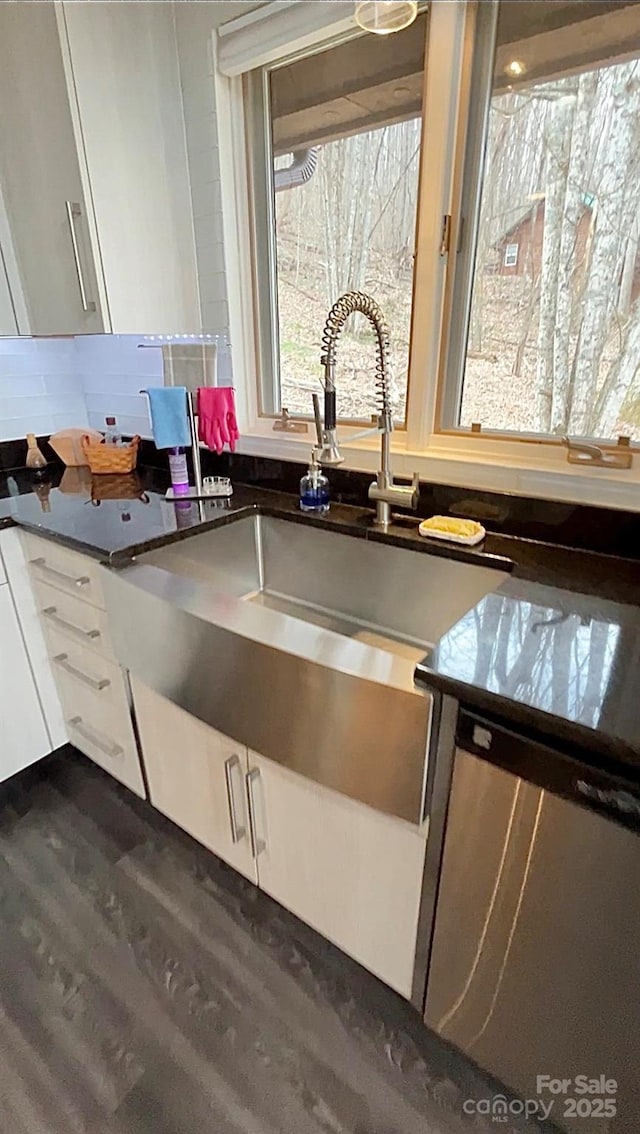 kitchen featuring dark wood-style floors, dark countertops, a sink, and white cabinets