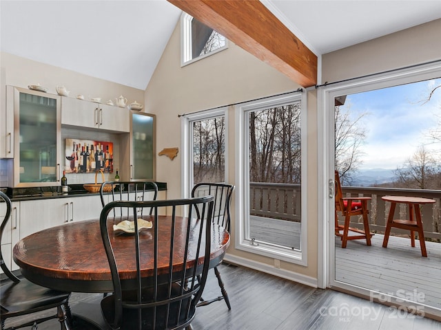 dining area with baseboards, bar, high vaulted ceiling, and dark wood-style flooring