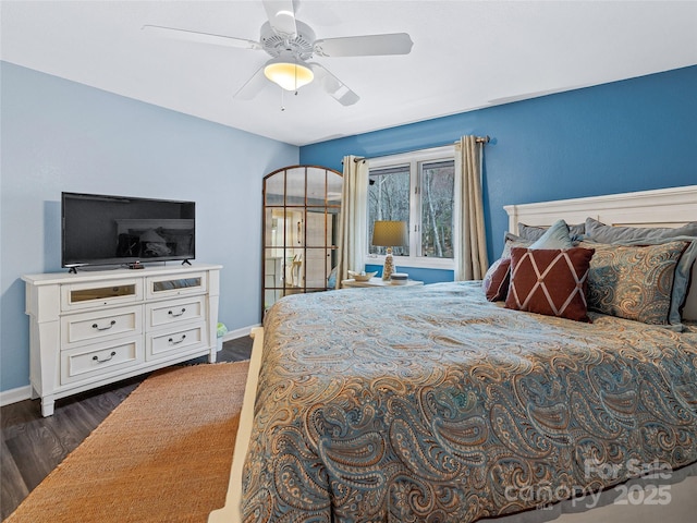 bedroom featuring dark wood-style floors, arched walkways, a ceiling fan, and baseboards