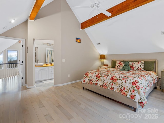 bedroom with a sink, light wood-style flooring, baseboards, and beam ceiling