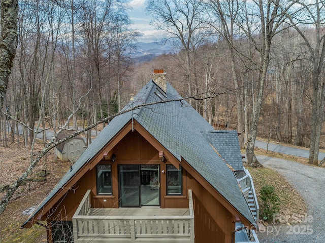 exterior space featuring roof with shingles and a chimney