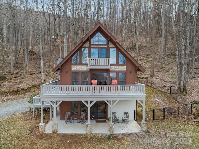 back of property featuring a patio area, fence, a wooded view, and a wooden deck