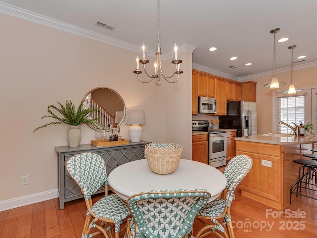 dining room with crown molding, visible vents, an inviting chandelier, light wood-type flooring, and baseboards