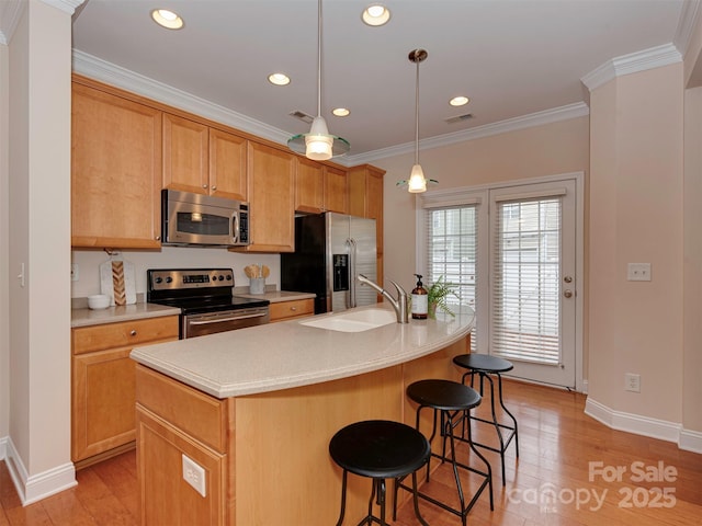 kitchen with light wood-type flooring, crown molding, appliances with stainless steel finishes, and a sink