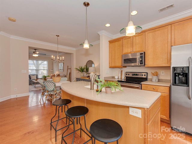 kitchen featuring stainless steel appliances, visible vents, ornamental molding, and light wood finished floors