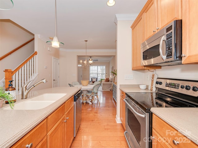 kitchen with appliances with stainless steel finishes, a sink, light wood-style flooring, and ornamental molding