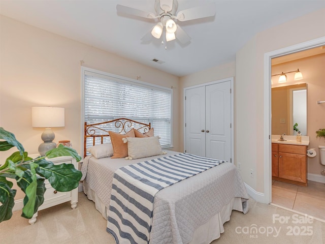 bedroom featuring connected bathroom, light carpet, a sink, visible vents, and a closet