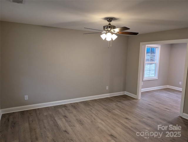 spare room featuring ceiling fan, baseboards, and wood finished floors