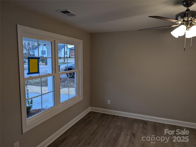 unfurnished room featuring ceiling fan, dark wood finished floors, visible vents, and baseboards