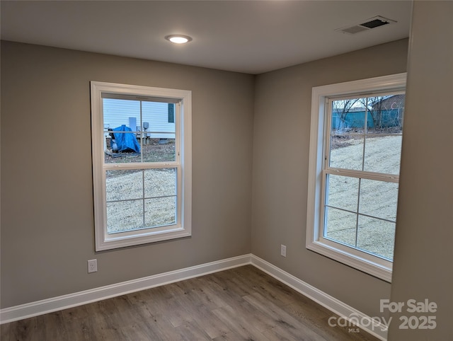 empty room featuring baseboards, visible vents, and wood finished floors