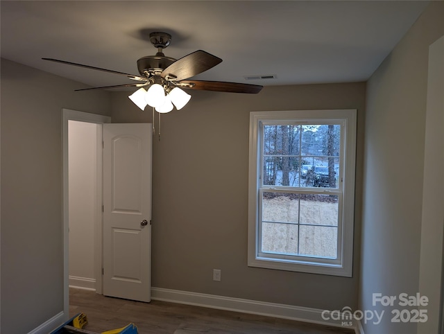 unfurnished room featuring baseboards, visible vents, a wealth of natural light, and wood finished floors