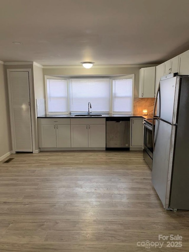 kitchen with visible vents, white cabinets, stainless steel appliances, light wood-type flooring, and a sink