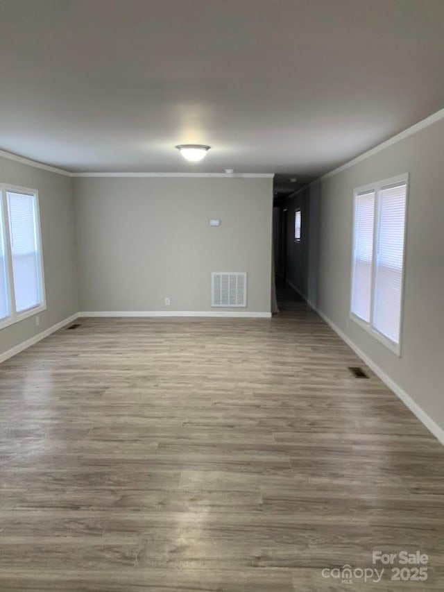 unfurnished room with visible vents, crown molding, and wood finished floors