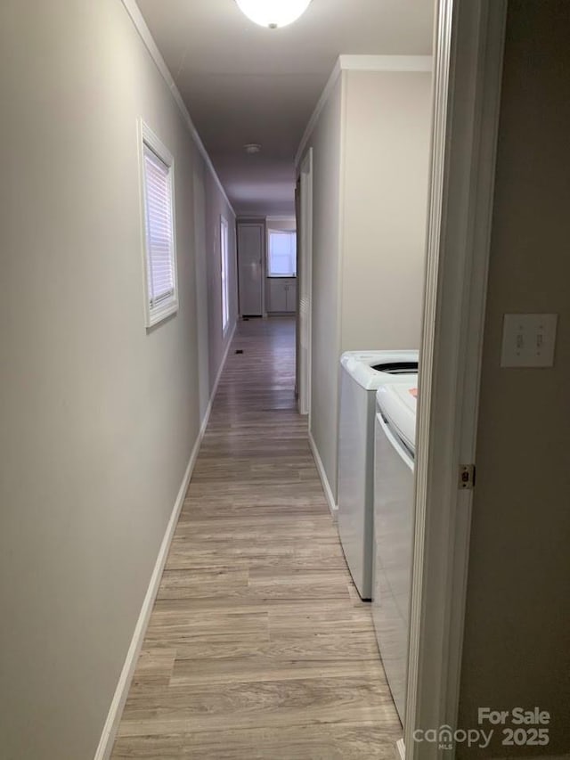 corridor with crown molding, baseboards, independent washer and dryer, and light wood finished floors