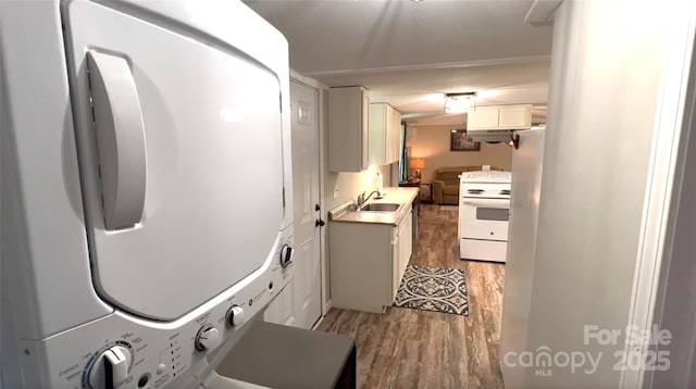 laundry room with light wood-type flooring, stacked washer / drying machine, laundry area, and a sink