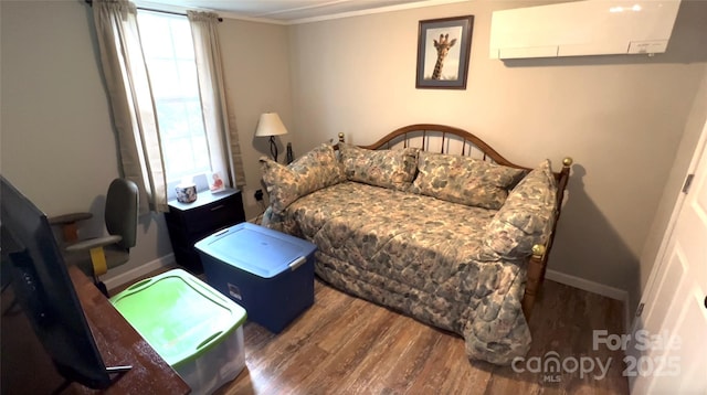 bedroom featuring baseboards, ornamental molding, wood finished floors, and a wall mounted air conditioner