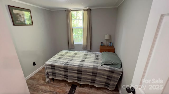 bedroom with crown molding, baseboards, and wood finished floors