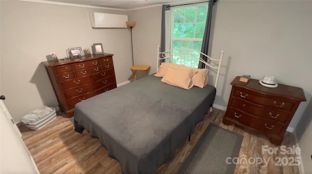 bedroom featuring ornamental molding, a wall mounted air conditioner, and wood finished floors