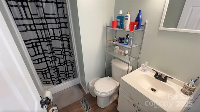 bathroom featuring curtained shower, visible vents, toilet, vanity, and wood finished floors