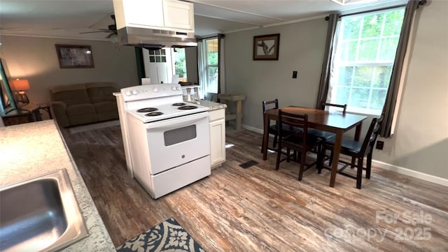 kitchen with wood finished floors, crown molding, under cabinet range hood, white cabinetry, and white range with electric cooktop