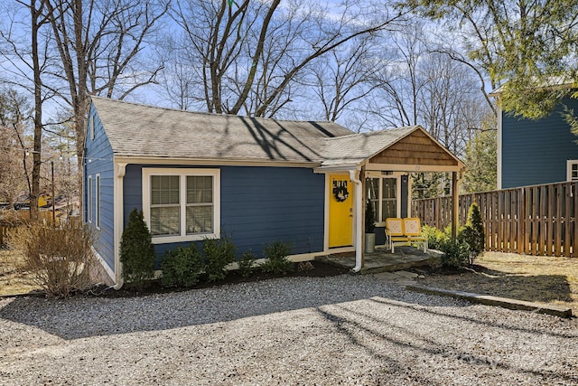 view of front facade featuring a shingled roof and fence