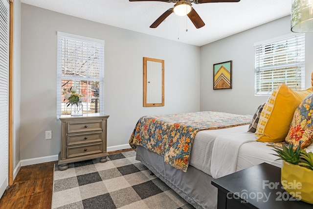 bedroom with multiple windows, wood finished floors, and baseboards