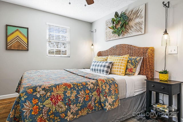 bedroom featuring a textured ceiling, wood finished floors, a ceiling fan, and baseboards