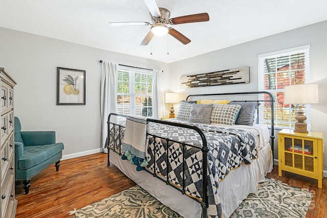 bedroom featuring ceiling fan, a textured ceiling, wood finished floors, and baseboards