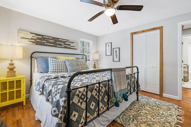 bedroom featuring ceiling fan, a closet, baseboards, and wood finished floors