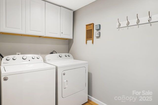 clothes washing area with cabinet space, washing machine and dryer, and baseboards